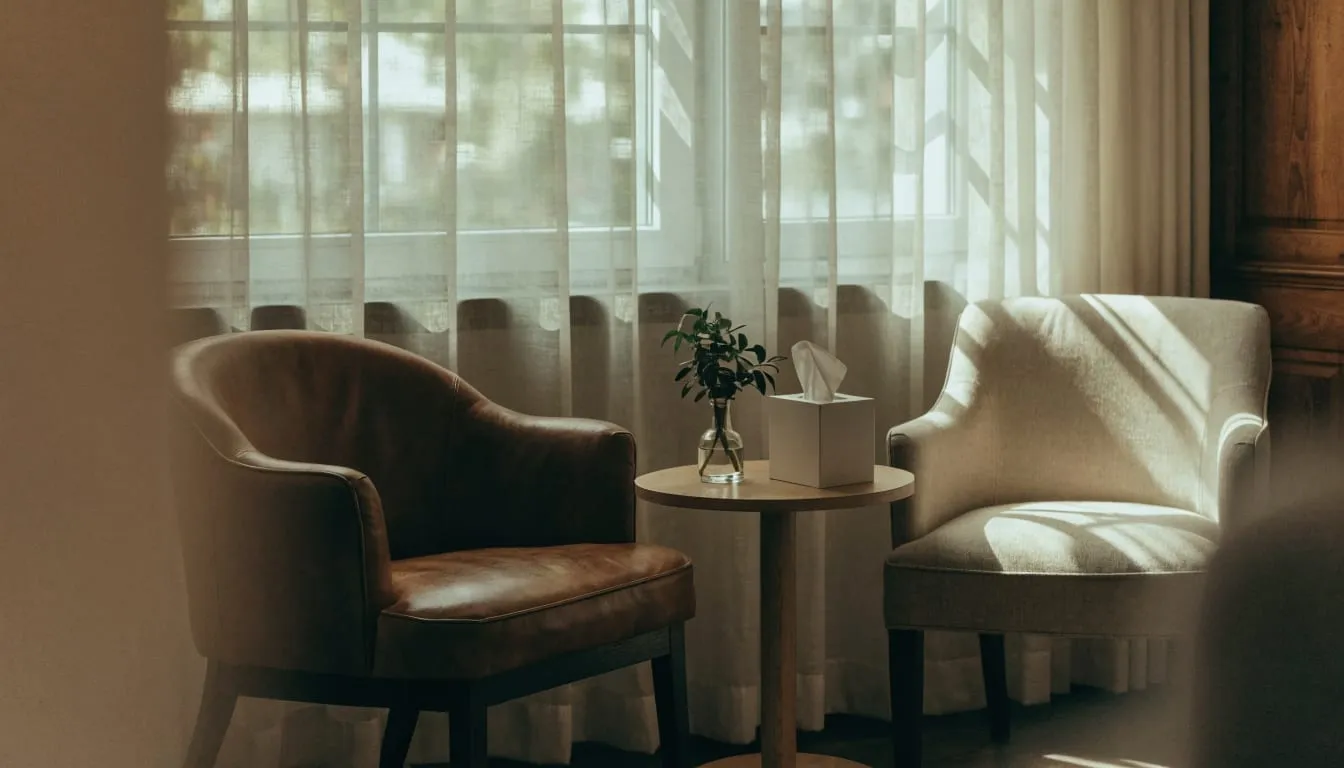Two armchairs face each other beside a large window with sheer curtains