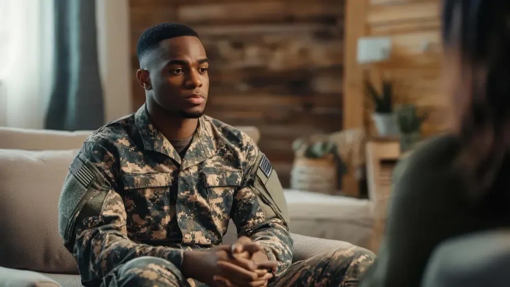 A soldier in uniform engages in a therapy session, seeking support for PTSD in a comfortable and supportive setting.