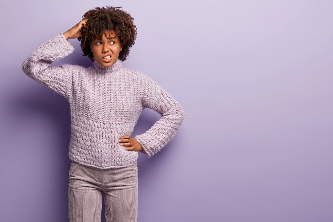 Someone scratches their head with a puzzled, overloaded expression against a purple background.