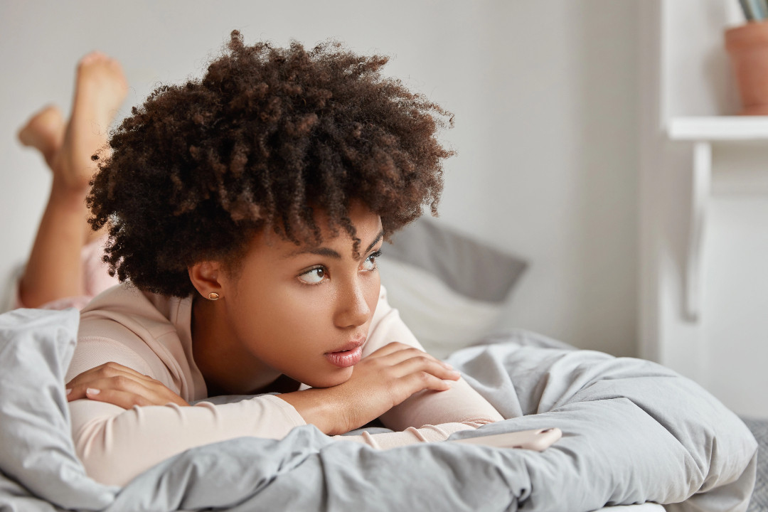 Someone lies awake on a bed, staring into the distance, unable to sleep.